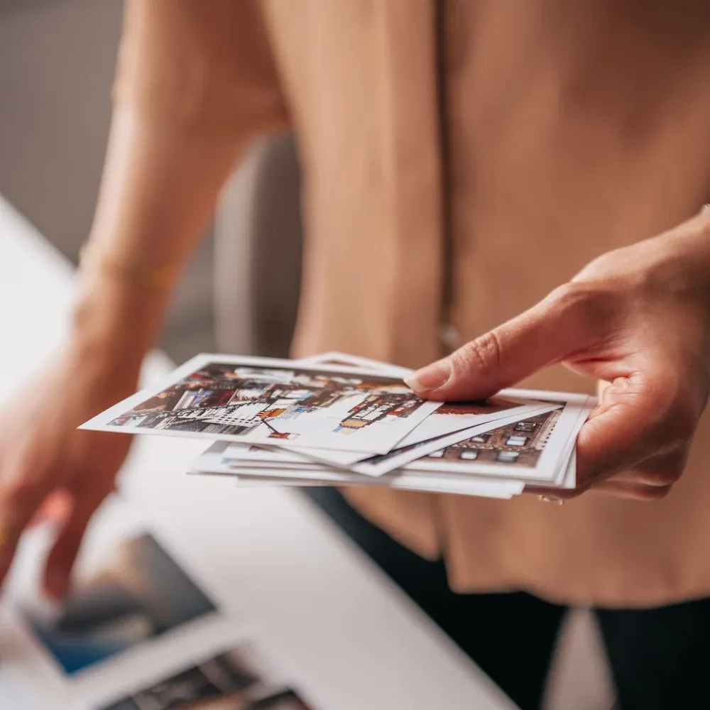 Mains feuilletant une pile de tirages photo, en gros plan sur les bords des images