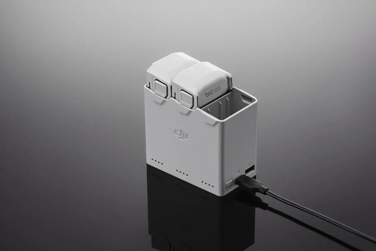 Station de charge blanche accueillant plusieurs batteries de drone, câble d’alimentation branché