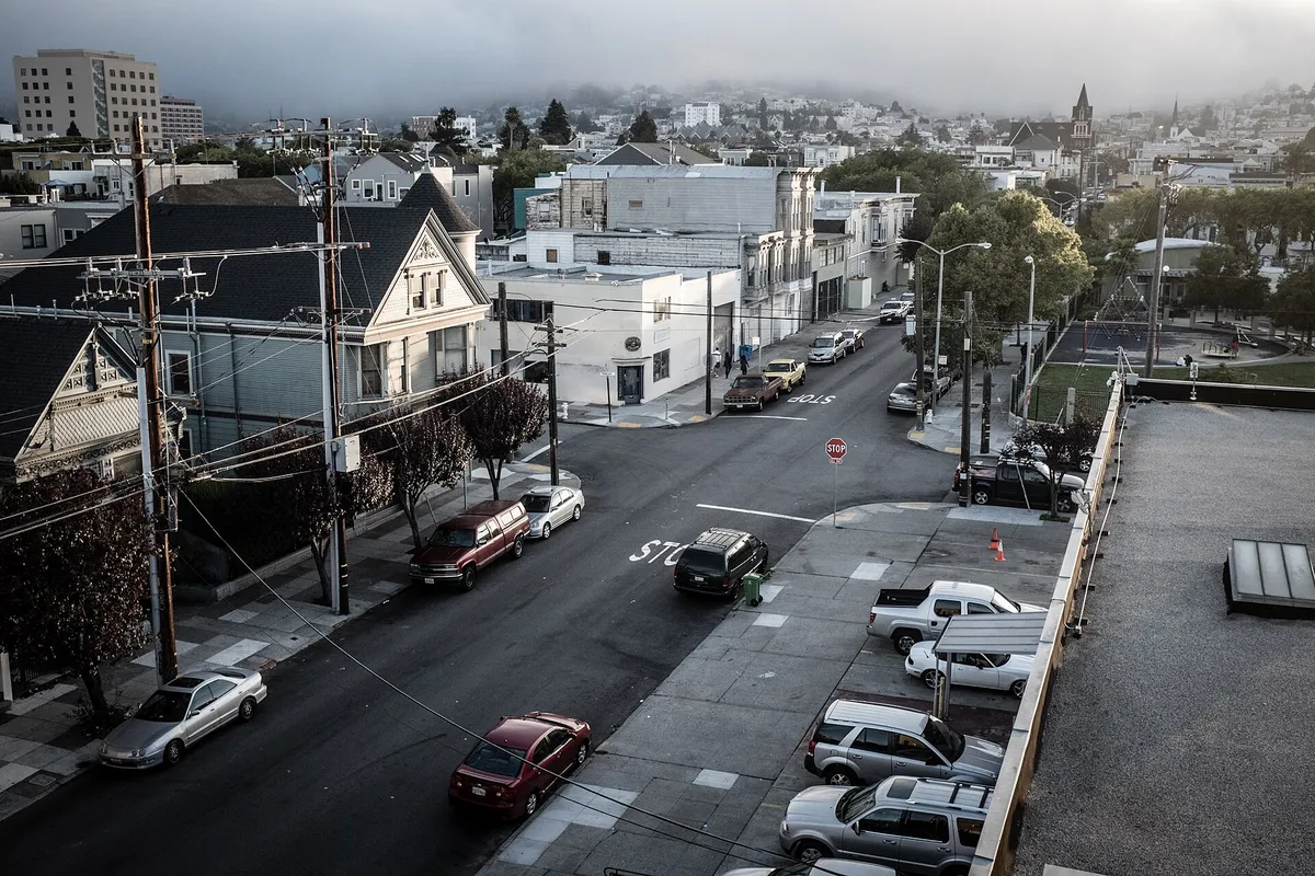 Quartier résidentiel en pente vu d’un toit, ses maisons et ses rues sous une brume basse