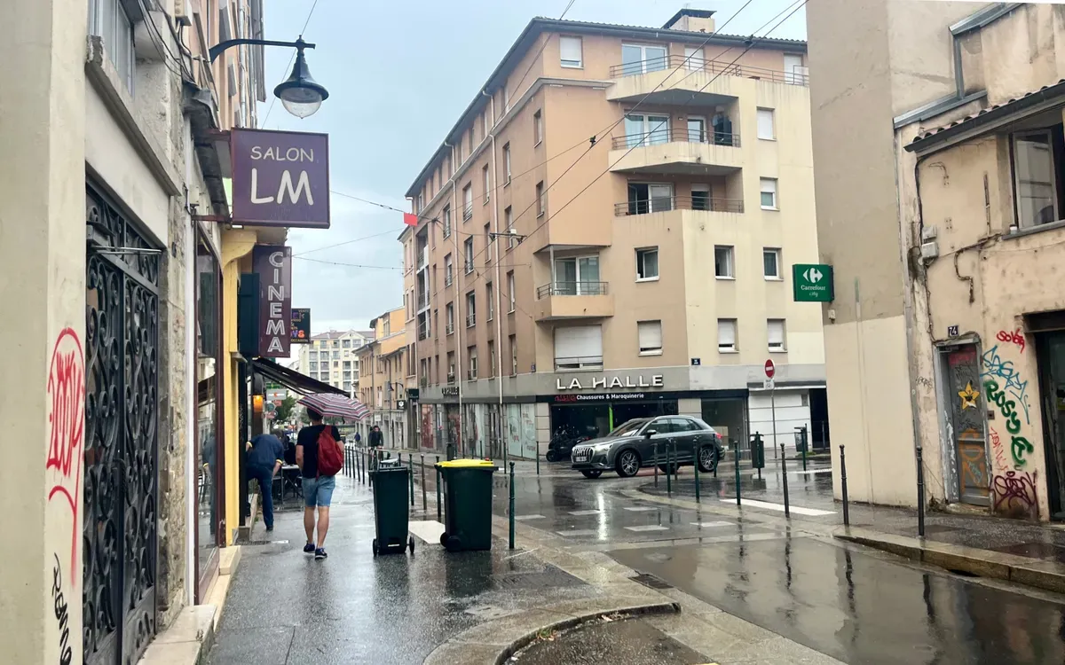 Rue en pente de la Croix-Rousse à Lyon sous la pluie, pavés mouillés et façades grises