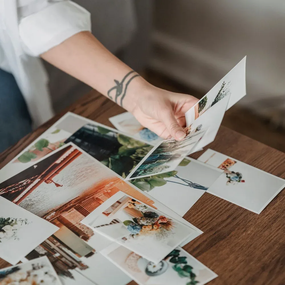 Main triant des tirages photo étalés sur une table en bois