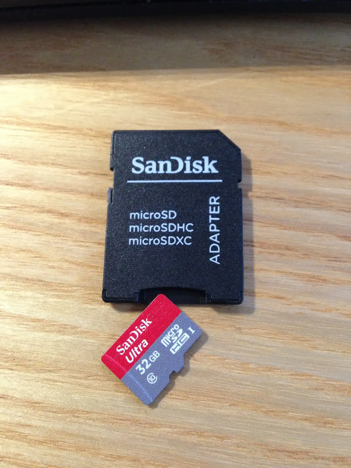 Carte microSD posée sur son adaptateur, sur un plan de travail en bois clair