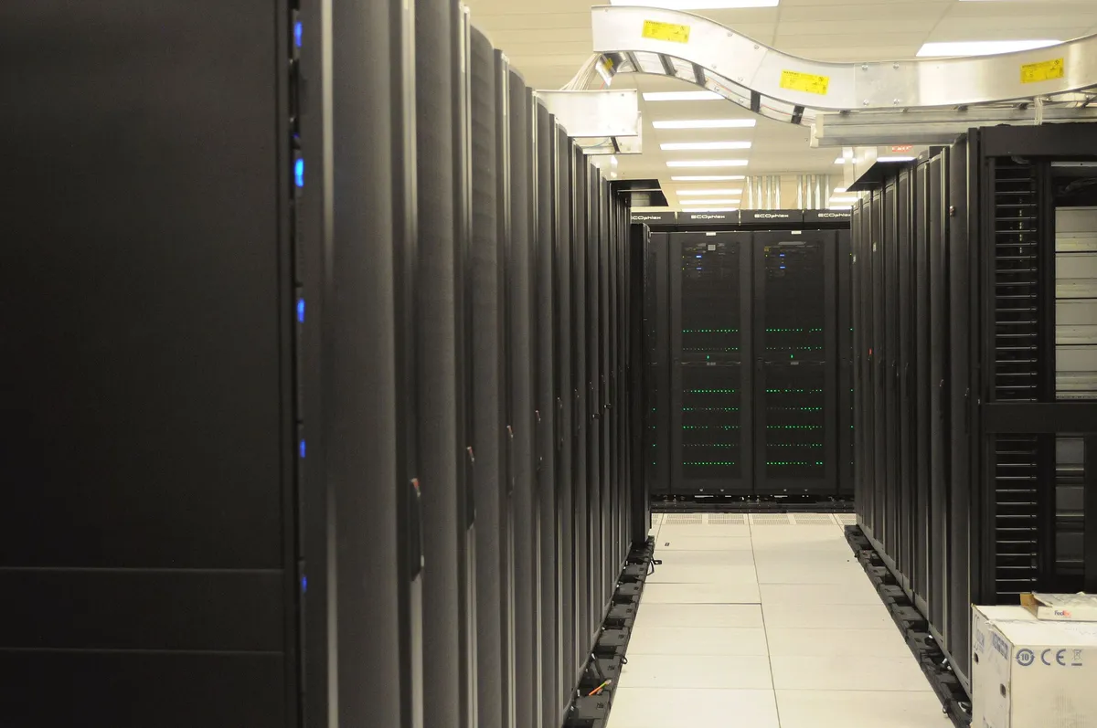 Allée de baies informatiques alignées dans une salle machine éclairée