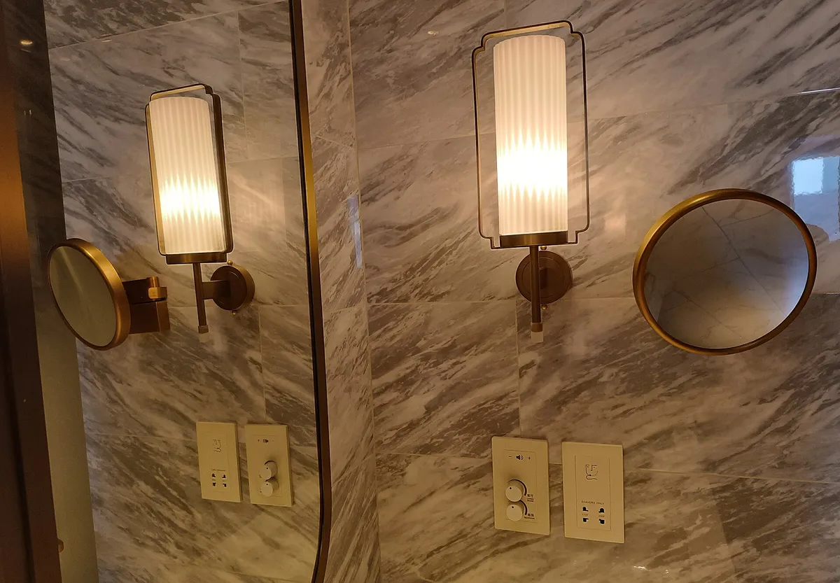 Two round mirrors and two wall lights on a pale marble wall