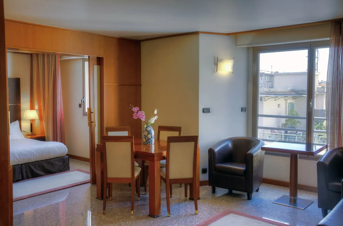 A flat’s room opening onto a balcony, a laid table and a dark armchair