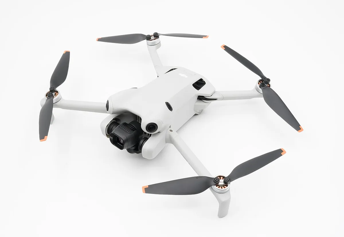 Drone amb un pes inferior a 250 grams amb les hèlixs desplegades, vist des de tres quarts sobre fons blanc