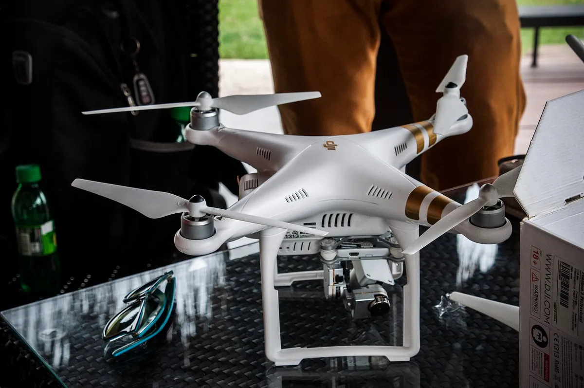 Dron blanc damunt d’una taula, hèlixs desplegades, a punt de sortir de reconeixement