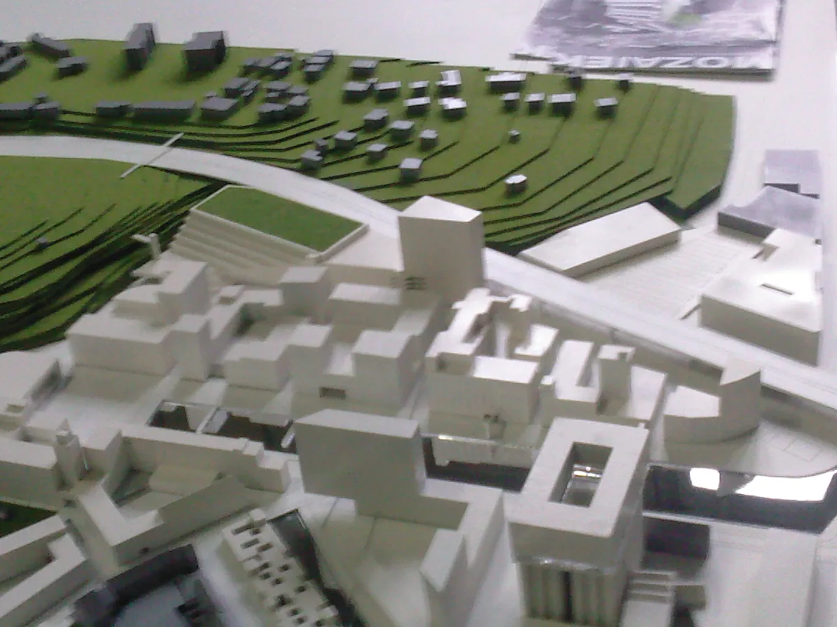 Maquette blanche d’un quartier posée à plat, avec un relief de terrain en carton vert